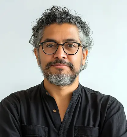 Man with curly hair and glasses wearing a black shirt.